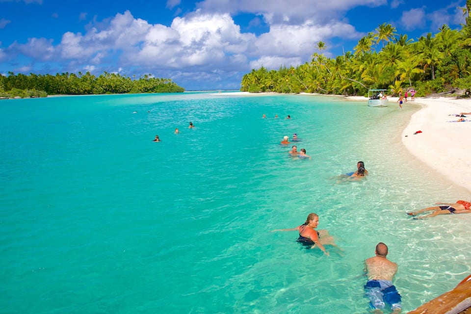 Una playa turquesa con gente nadando y tomando el sol.
