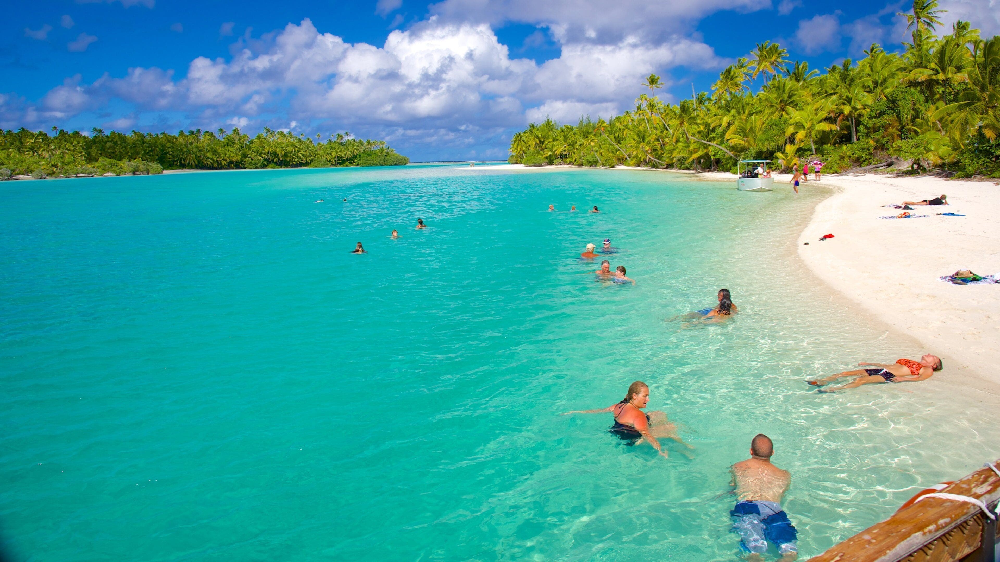 A turquoise beach with people swimming and sunbathing.