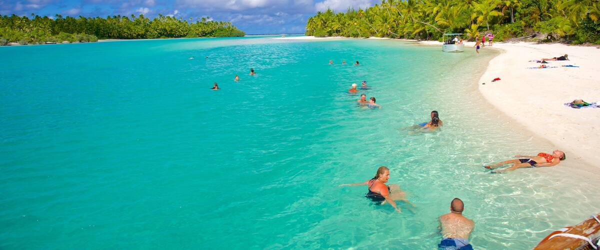 A turquoise beach with people swimming and sunbathing.