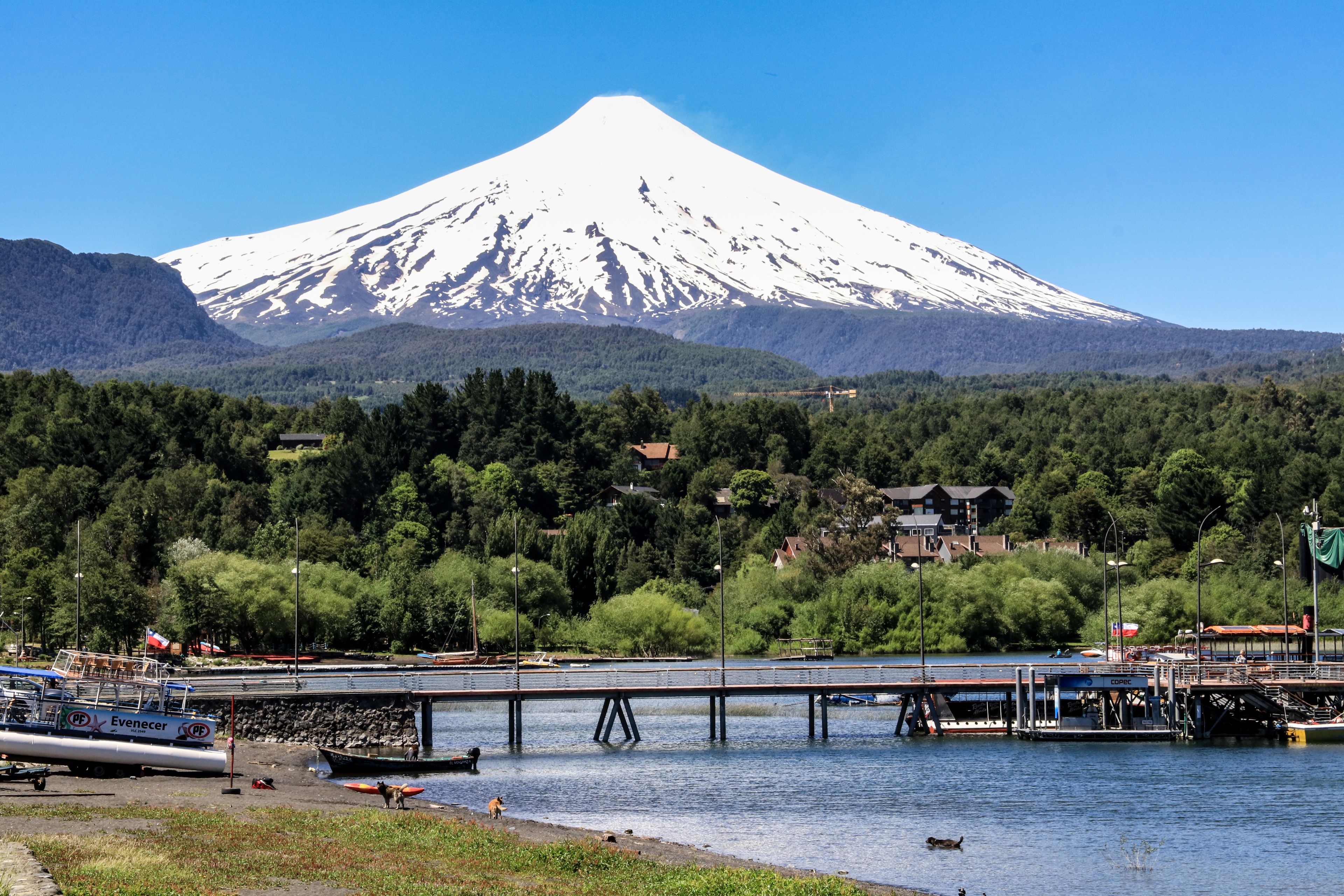 A snow-capped mountain, a river with boats, and a bridge.