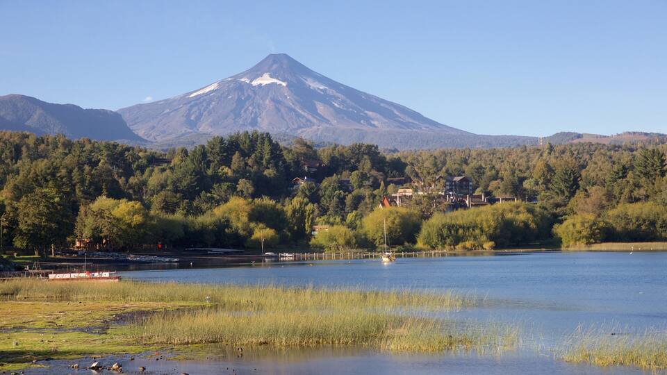 A lake with a mountain in the background, surrounded by trees and houses.