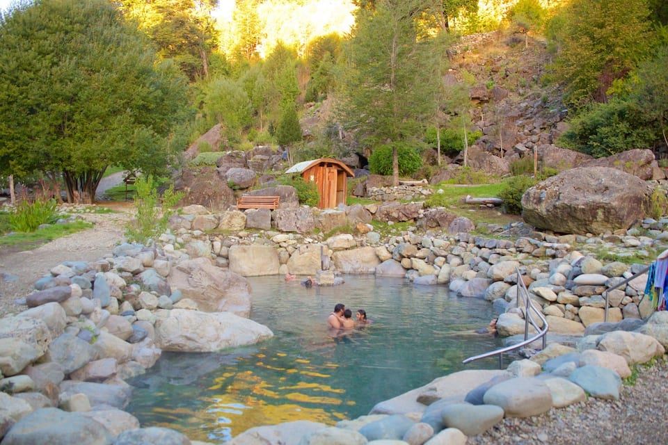 A natural hot spring surrounded by rocks and trees.