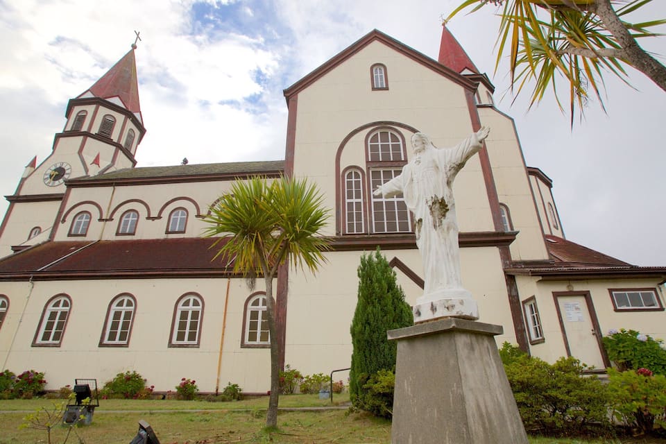 Una iglesia con campanario y una estatua en su fachada.