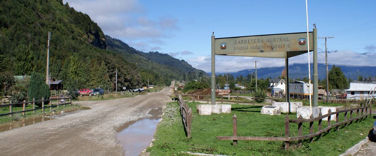 A rural road with a sign reading "CARRETERA AUSTRAL GENERAL AUGUSTO PINCHETIL".