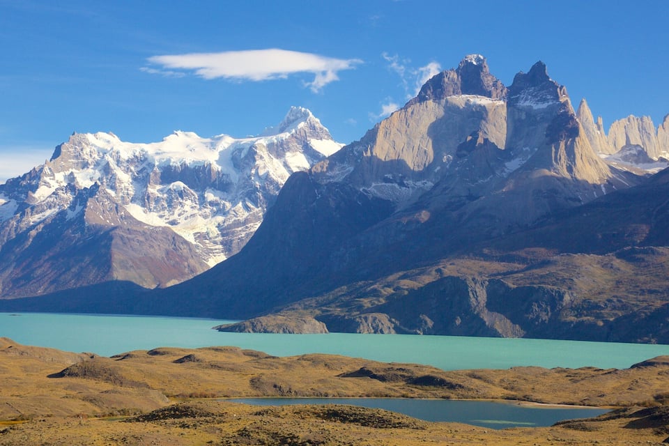 A mountainous landscape with snow-capped peaks and a turquoise lake.