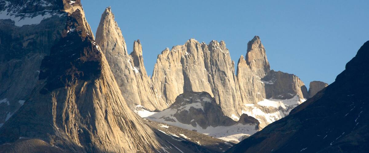 A rugged mountain range with sharp peaks and patches of snow.