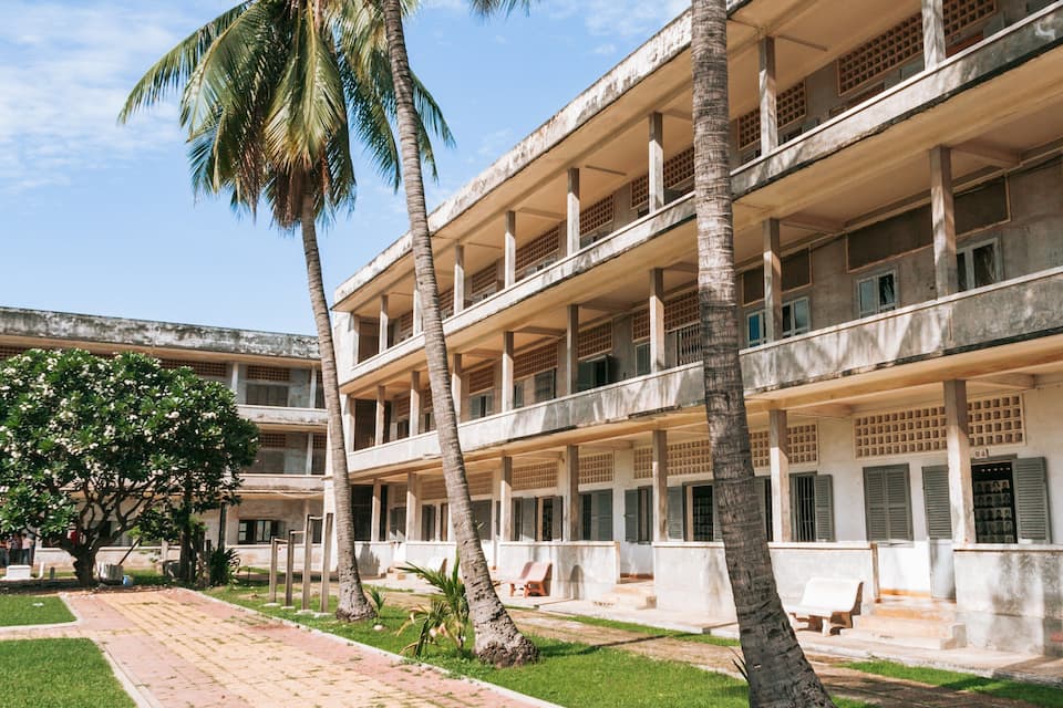 Un edificio de varios pisos con un patio, palmeras y un sendero.