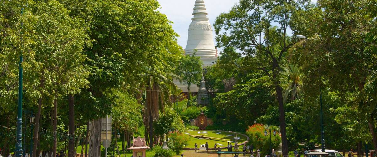 A street lined with trees and a white pagoda in the background.