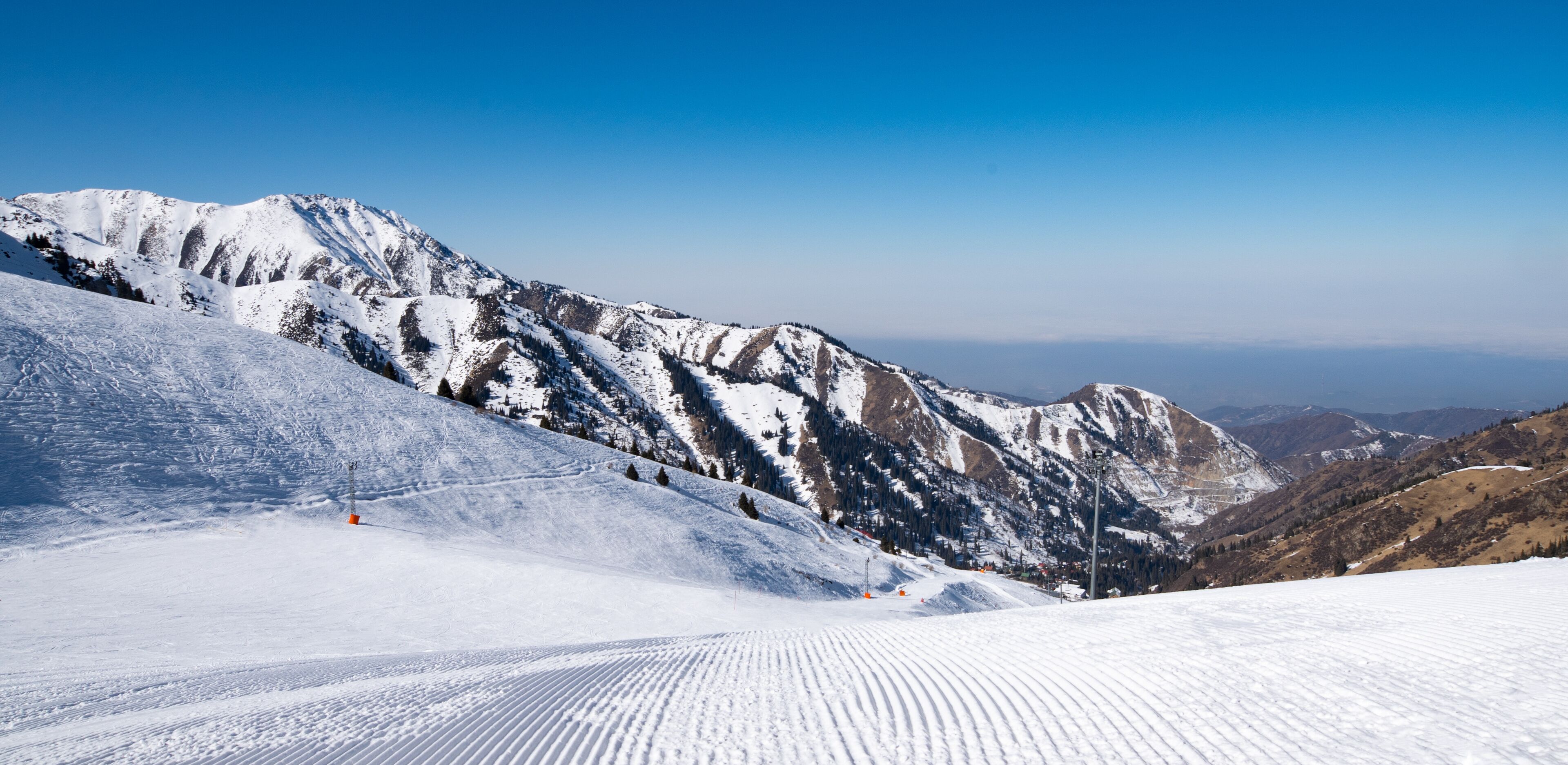 Famous Shymbulak mountain ski resort view with beautiful white and snowy ski lines, blue sky, fresh air. Wonderful picturesque resort for holidays, travelling and sport near Almaty. 