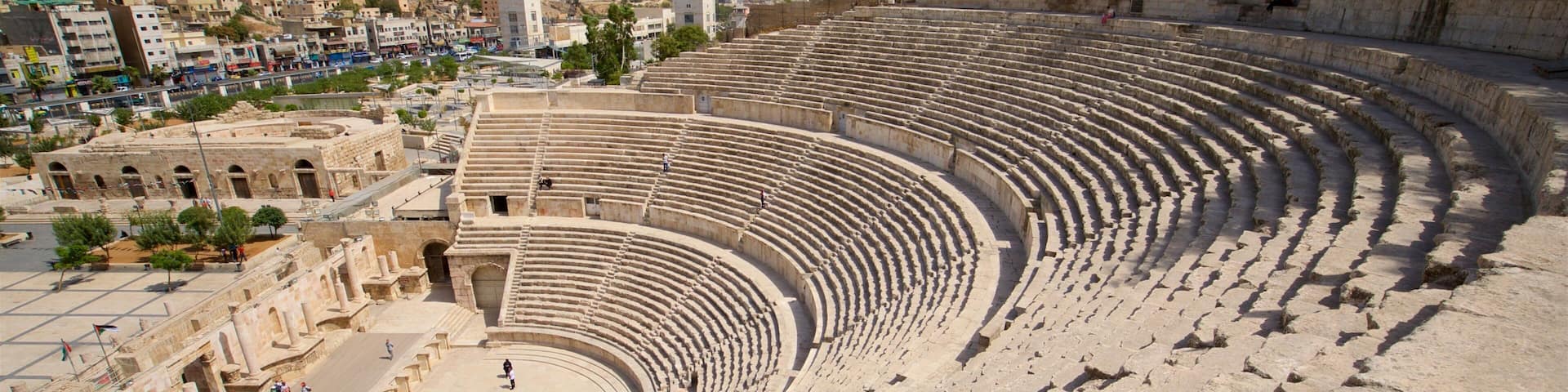 An ancient amphitheater with tiered seating and ruins.