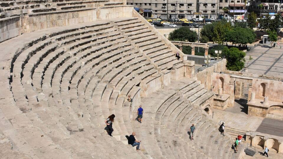 Ein antikes Amphitheater mit Steinstufen und einigen Zuschauern.