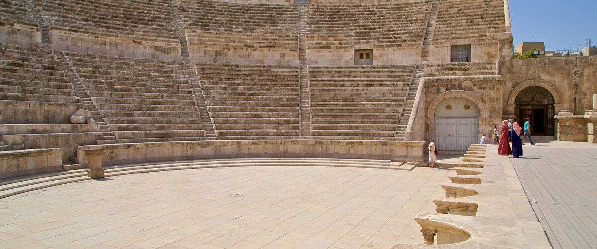 An ancient stone amphitheater with tiered seating and a central stage.