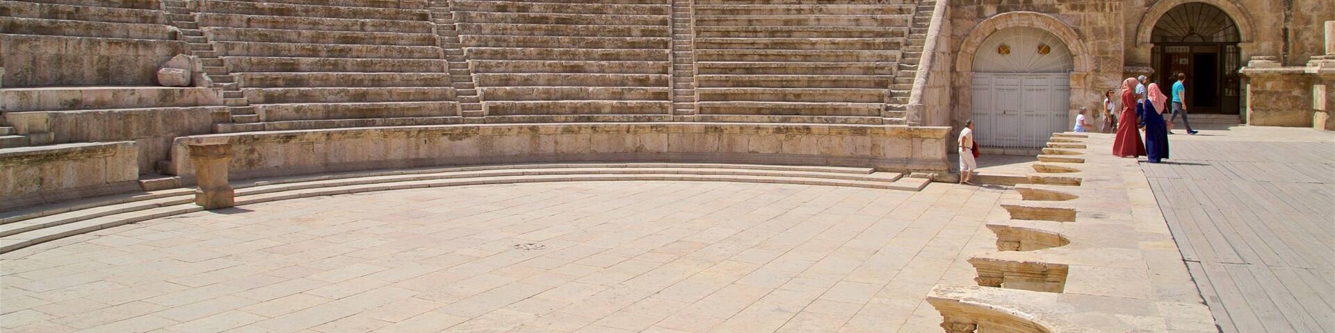 An ancient stone amphitheater with tiered seating and a central stage.