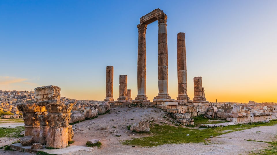 Ancient ruins with columns and stone structures against a clear sky.