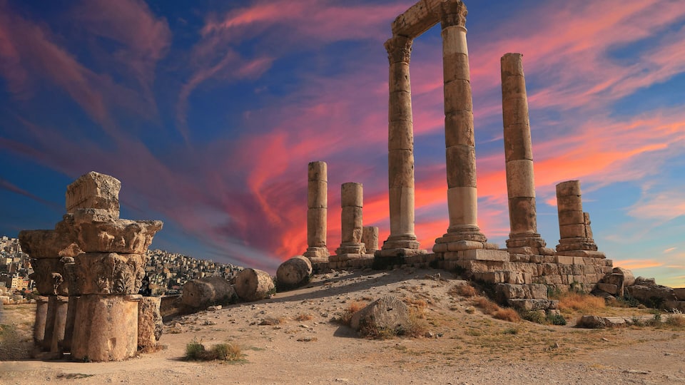Columnas de piedra antiguas y ruinas al atardecer.