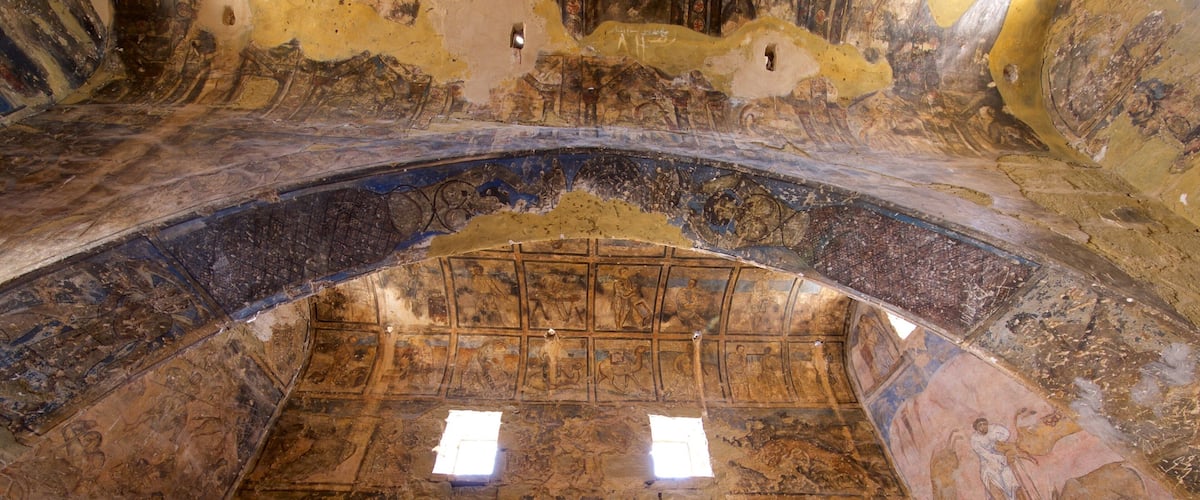 An ancient, arched ceiling with intricate mosaics and a central skylight.