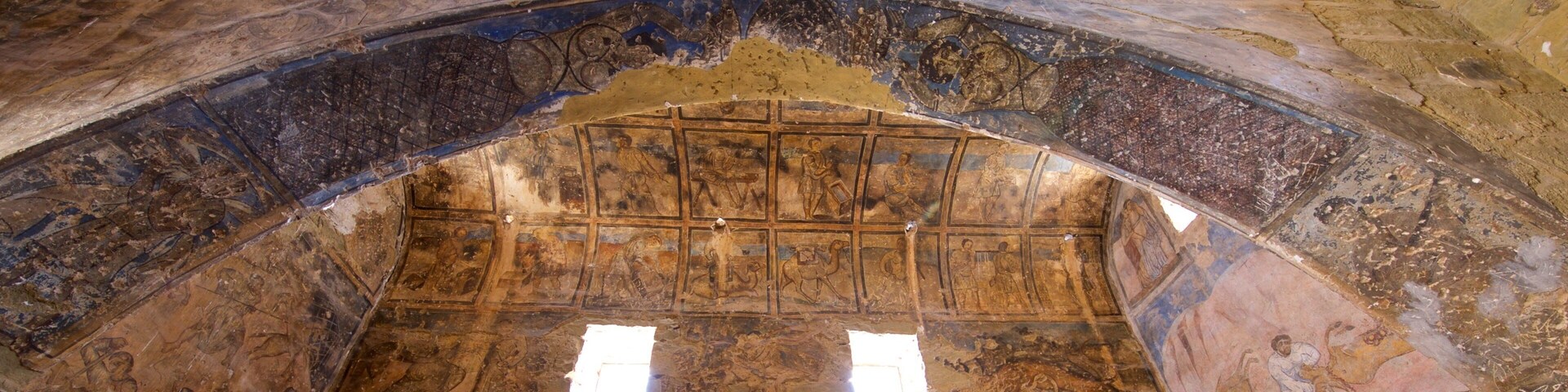 Teto antigo em arco, com mosaicos detalhados e um claraboia central.