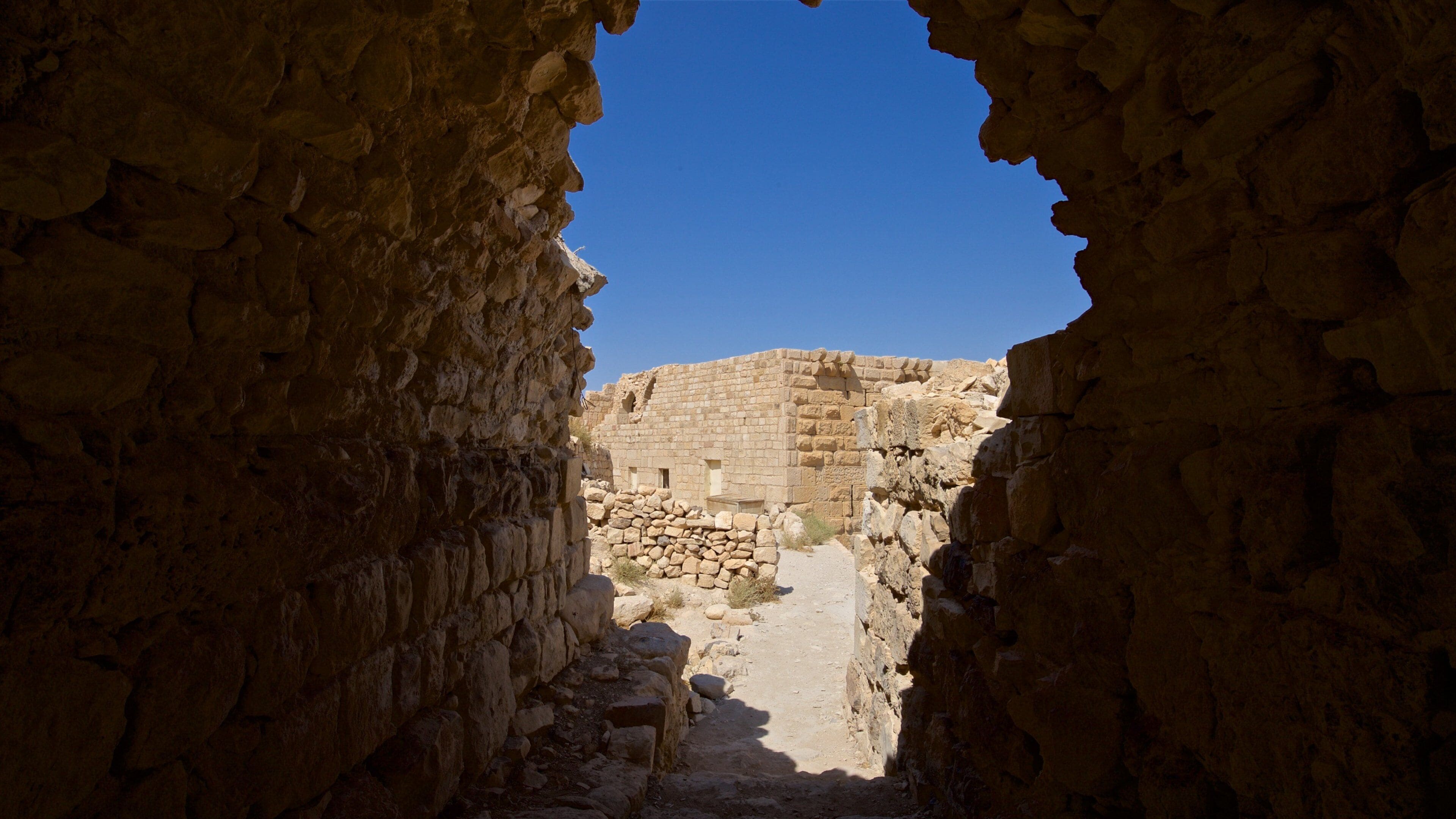 An ancient stone structure with a narrow passageway leading to a larger building.