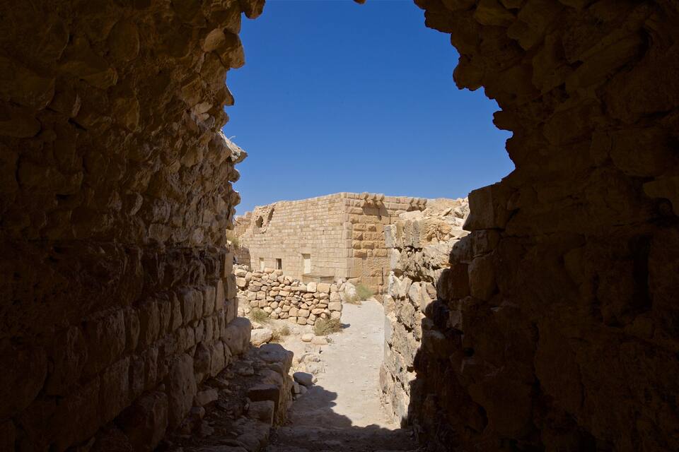 An ancient stone structure with a narrow passageway leading to a larger building.