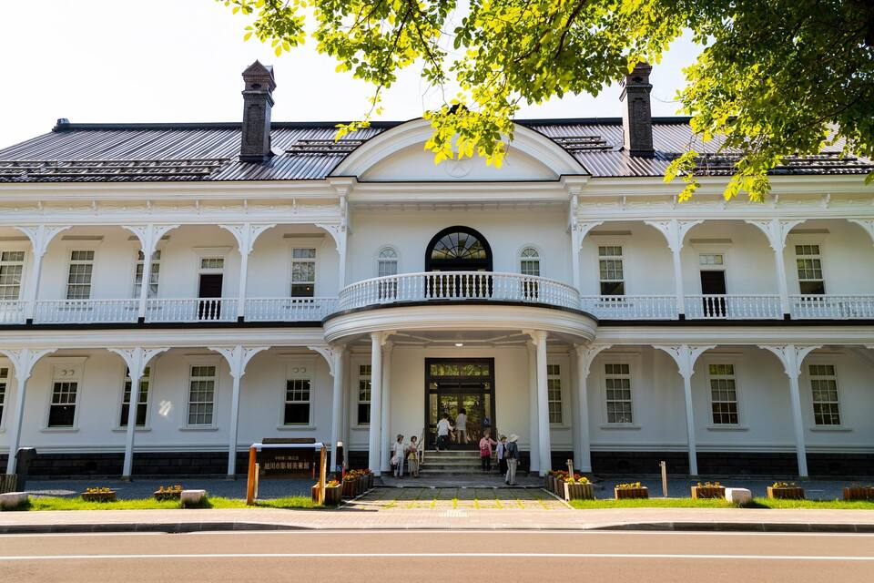 A large white building with a central entrance and multiple balconies.