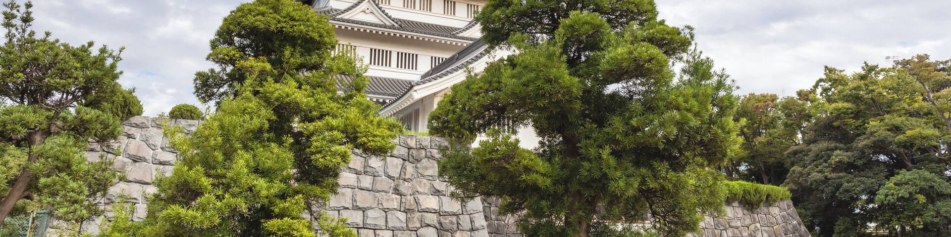 A traditional Japanese castle with multiple tiers and a stone wall in the foreground.