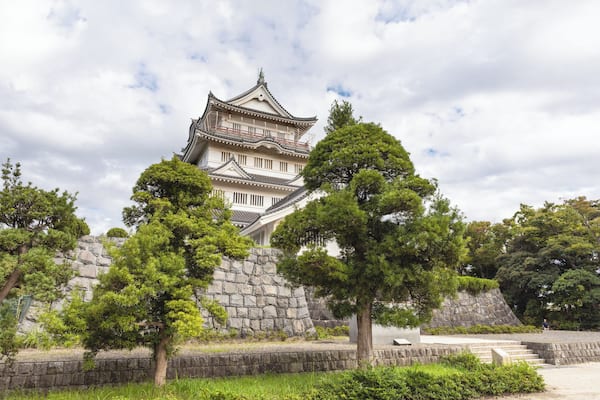 Un château japonais traditionnel, doté de plusieurs niveaux et d’un mur de pierre en premier plan.