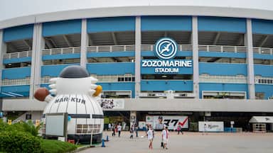 La façade extérieure du stade Zozomarine, avec une grande mascotte gonflable et des personnes qui se promènent.