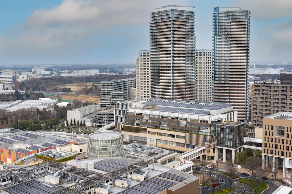 Un paysage urbain avec des immeubles modernes de grande hauteur, des panneaux solaires et une université.