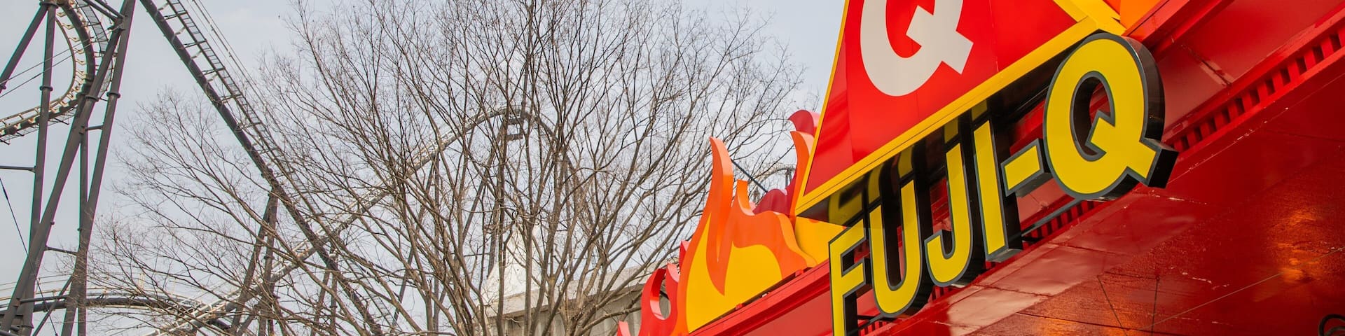 A roller coaster and a red and yellow sign with the letters "Q" and "FUJI-Q".