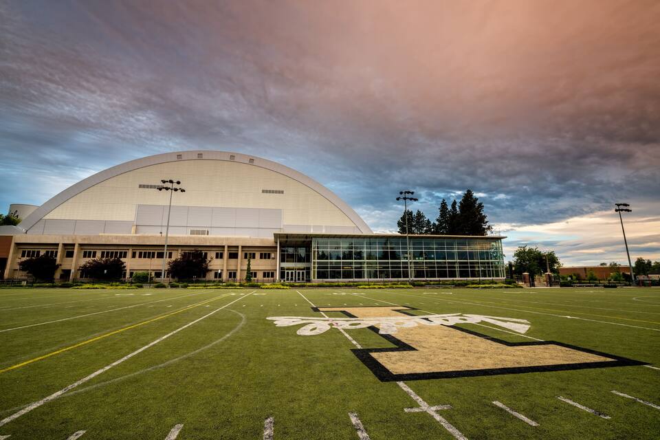 A football field with a large stadium in the background.