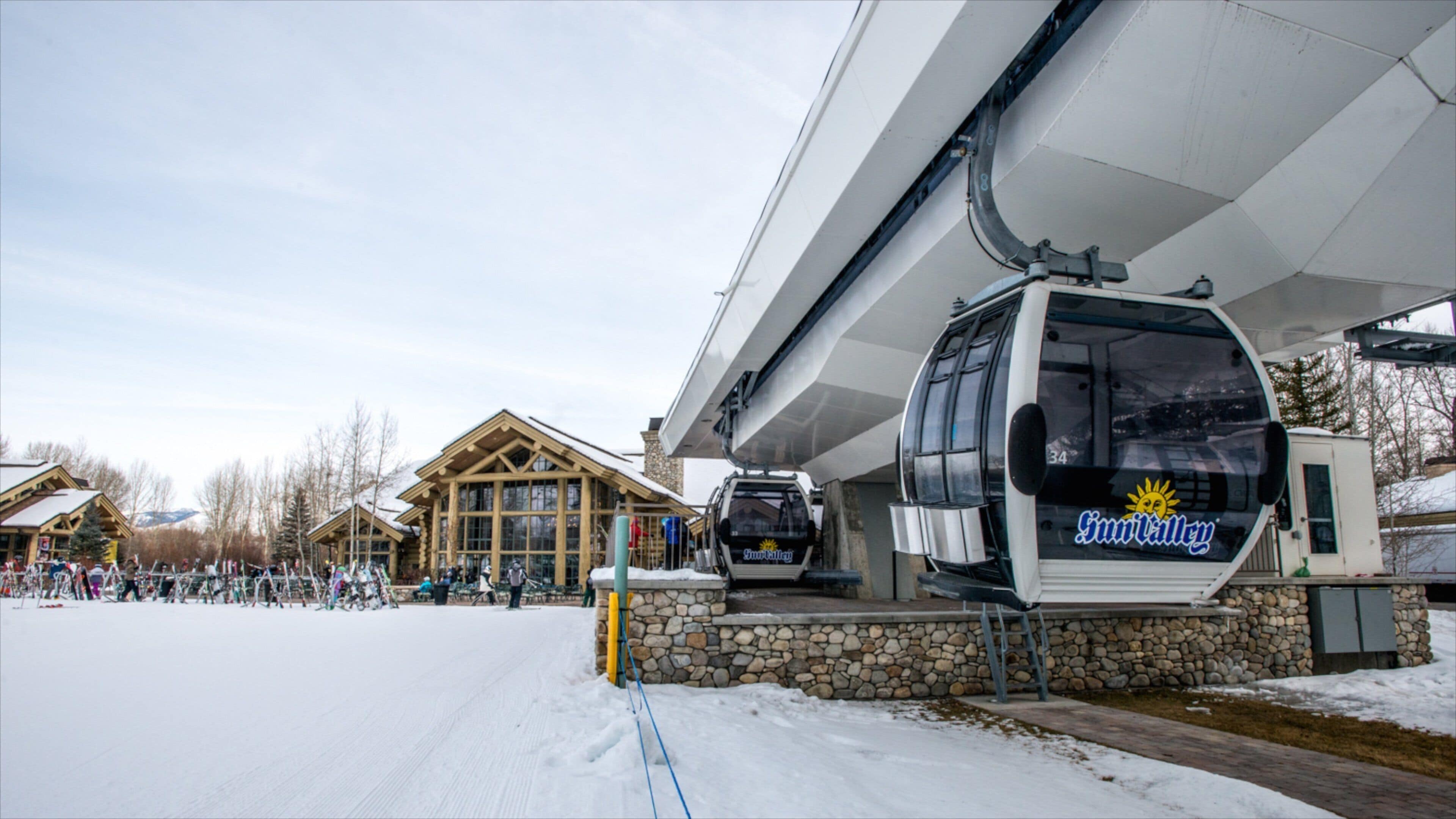 A ski lift station with a cable car, wooden buildings, and a snowy landscape.