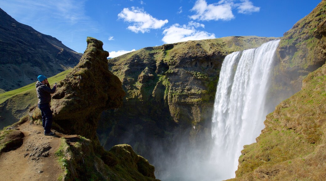 Skogafoss showing a cascade and a gorge or canyon as well as an individual male