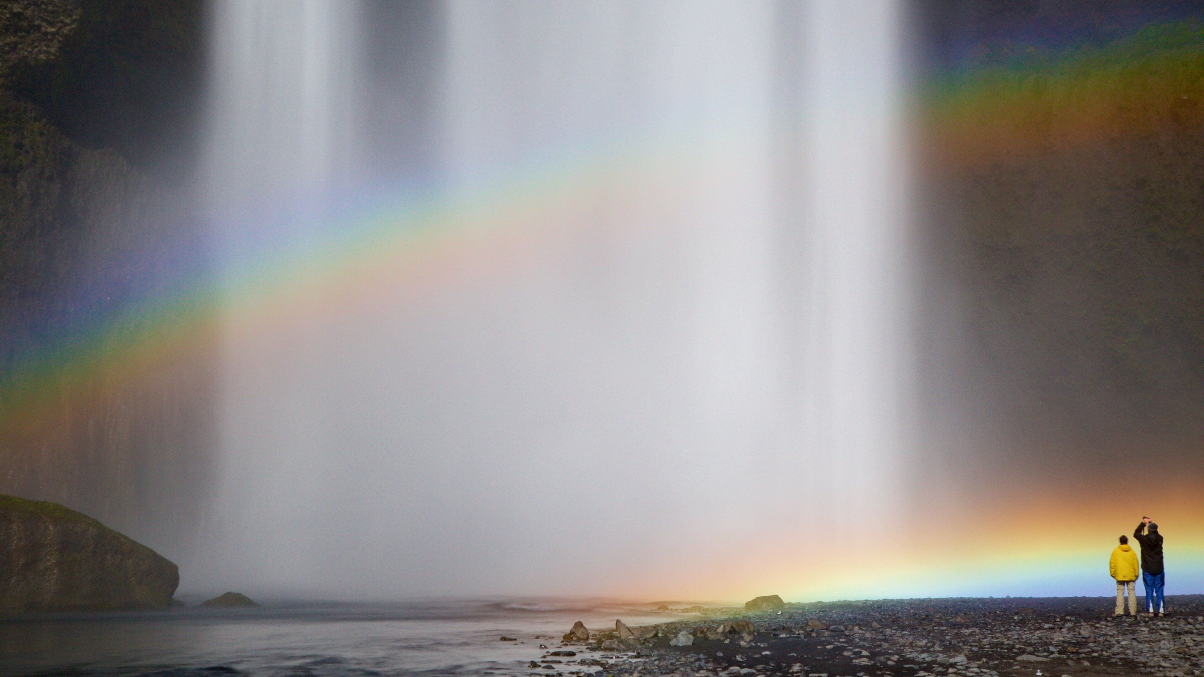 Skogafoss featuring a waterfall as well as a small group of people