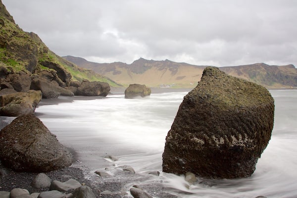 Un littoral rocheux, parsemé de gros blocs de pierre, et une mer calme.