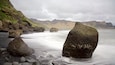 Un littoral rocheux, parsemé de gros blocs de pierre, et une mer calme.