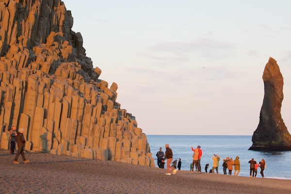 Reynisdrangar featuring general coastal views and a sunset as well as a large group of people