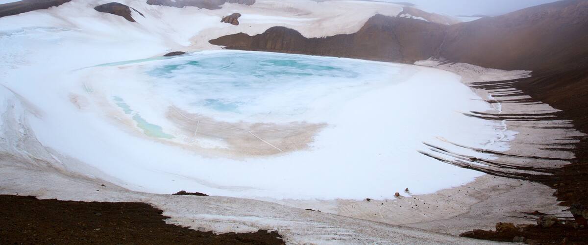 Krafla Volcano featuring a hot spring and snow