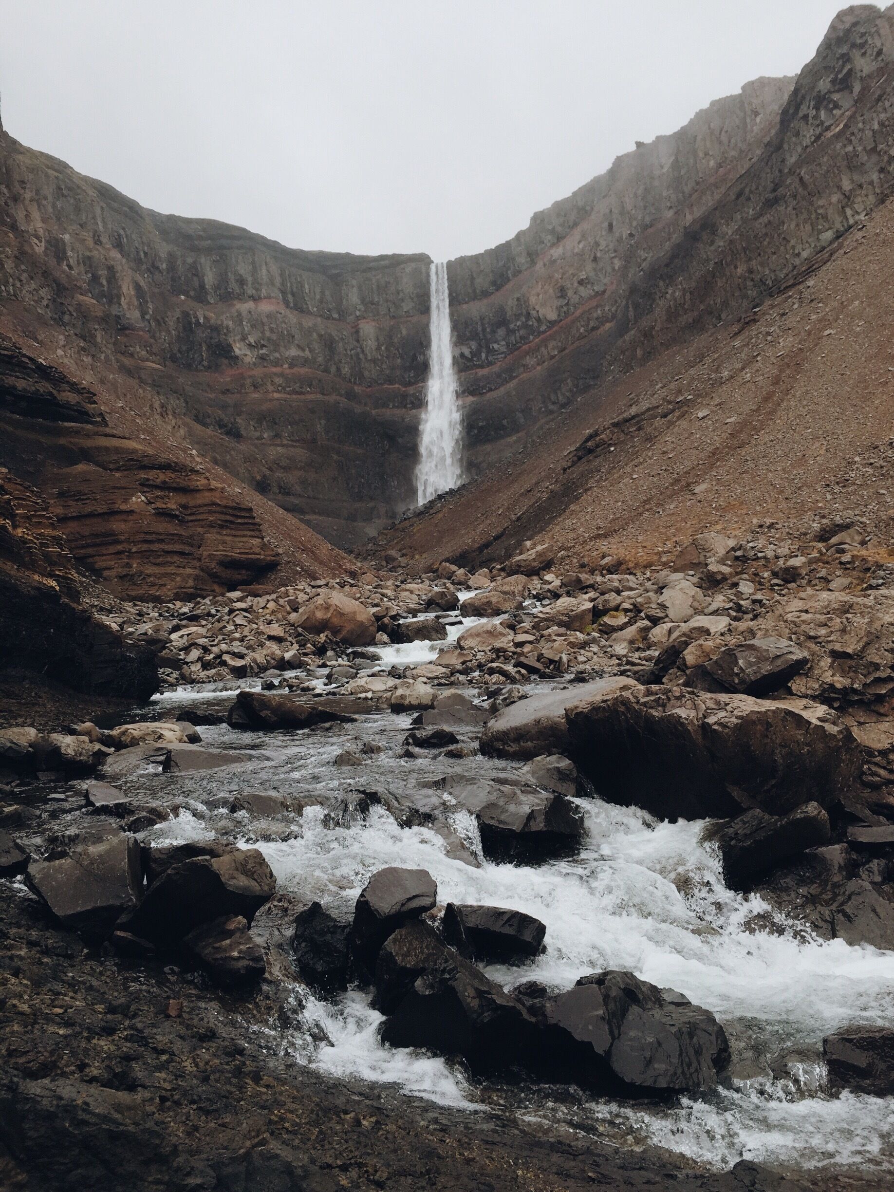 A waterfall cascading down a rocky gorge with a river flowing through it.