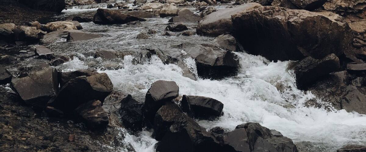 A waterfall cascading down a rocky gorge with a river flowing through it.
