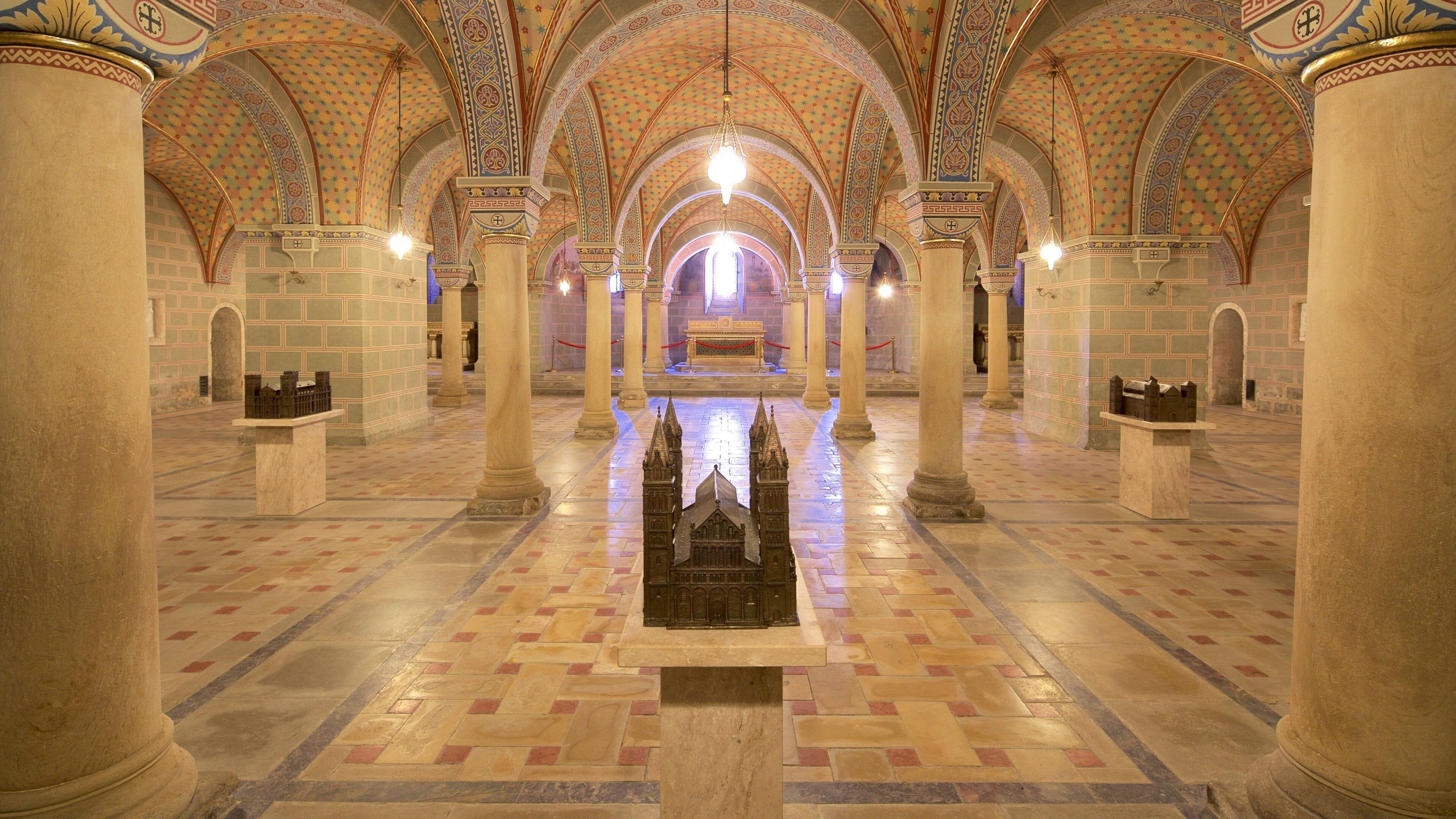 An interior with a central aisle, ornate columns, and a detailed ceiling.
