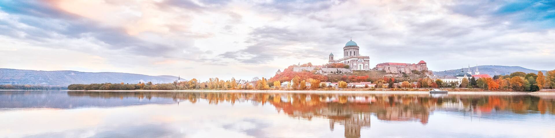 Esztergom, Hungary - view over Danube river from Sturovo, Slovakia. Epic sunrise landscape with dramatic sky of famous Basilica Esztergom. Amazing reflections of clouds. Red and blue colors scenery.