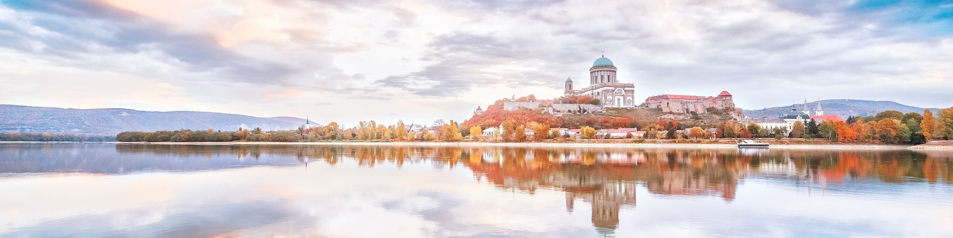 Esztergom, Hungary - view over Danube river from Sturovo, Slovakia. Epic sunrise landscape with dramatic sky of famous Basilica Esztergom. Amazing reflections of clouds. Red and blue colors scenery.