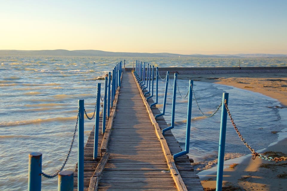A wooden pier with blue railings leading to a beach.