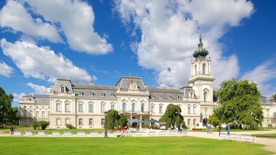 A large historic building with a prominent tower and a well-maintained garden with benches.