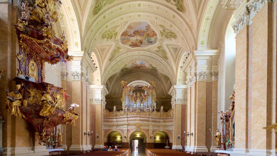 An ornate church interior with high ceilings, detailed frescoes, and golden statues.