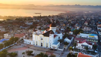 A coastal cityscape with a prominent church featuring a large dome and bell tower, surrounded by dense urban buildings and a calm sea.