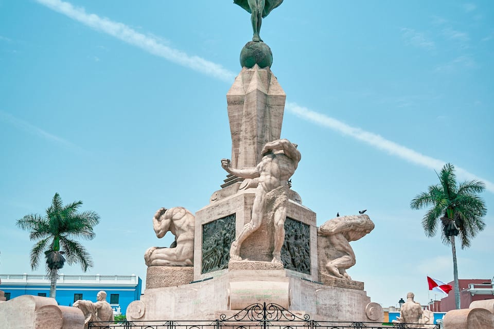 Una gran estàtua amb una figura que sosté una corona de llorer, flanquejada per dos lleons, i una escala que hi mena.