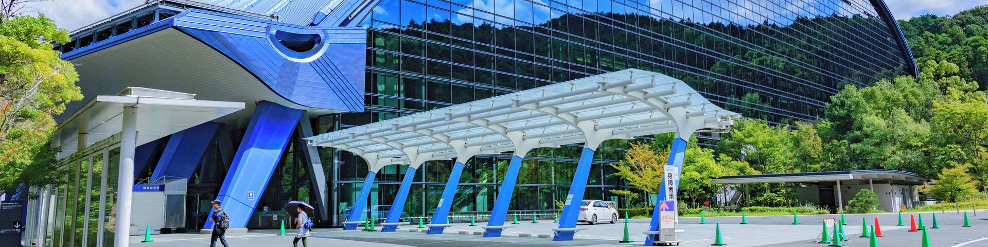 A modern glass building with a curved roof and blue accents.