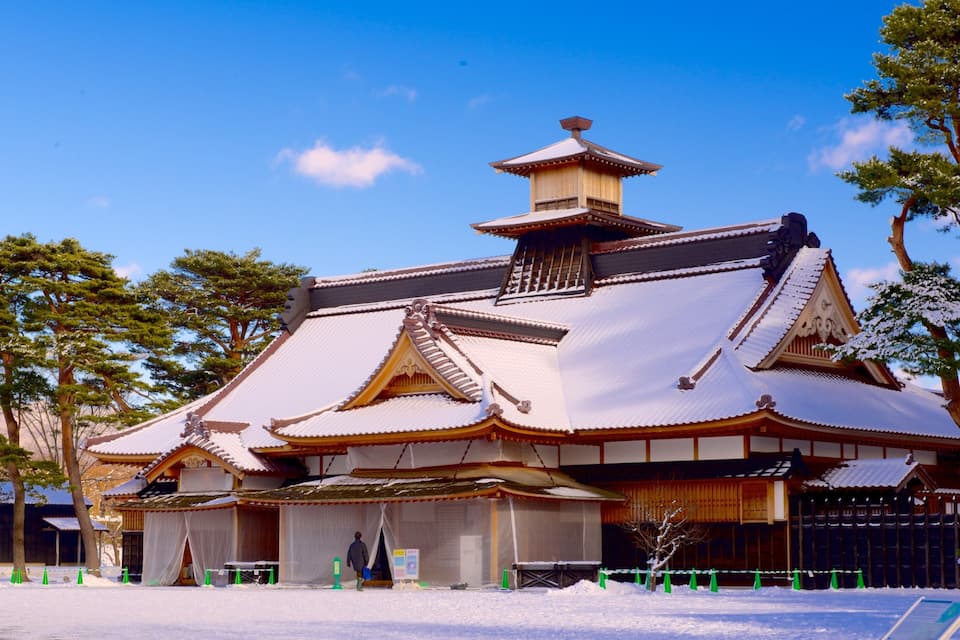 Un edificio tradicional japonés con tejado nevado y arquitectura de madera.