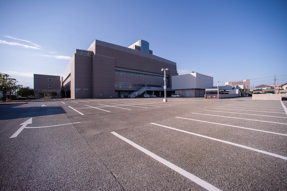 A large parking lot with marked parking spaces and a building with a ramp and stairs.